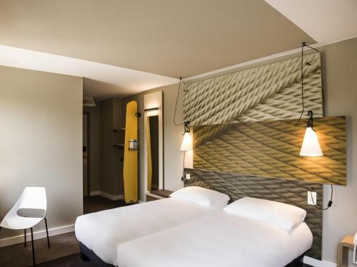ワーヴルにあるIbis Wavre Brussels Eastのベッドルーム1室(白いベッド2台付)と黄色い壁が備わります。