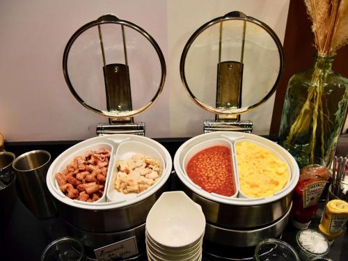 a counter with three pans of different types of food at Mercure Cholet Centre in Cholet