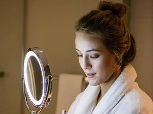 a woman in a towel looking at a mirror at Mercure Curitiba Batel in Curitiba