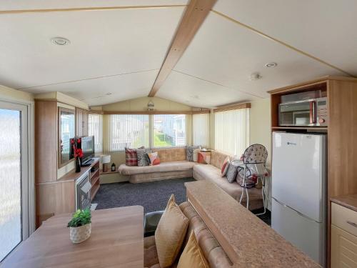 a living room with a couch and a kitchen at Cozee Stays in Rhyl