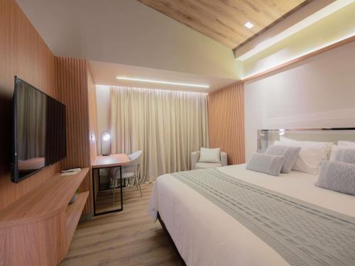 a hotel room with a bed and a flat screen tv at Mercure Curitiba Batel in Curitiba
