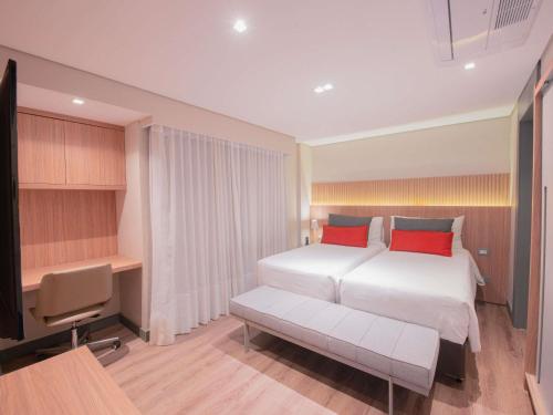 a bedroom with a bed and a desk and a television at Mercure Curitiba Batel in Curitiba