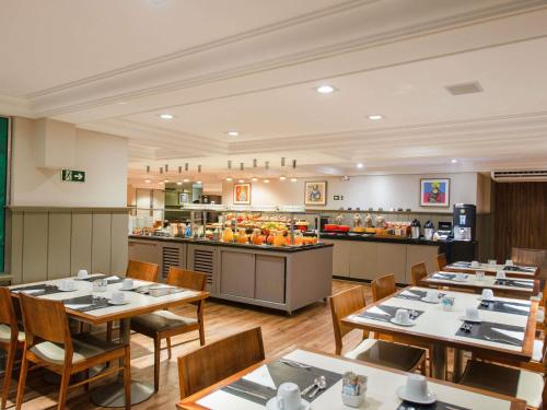 a restaurant with tables and chairs and a buffet at Mercure Curitiba Batel in Curitiba