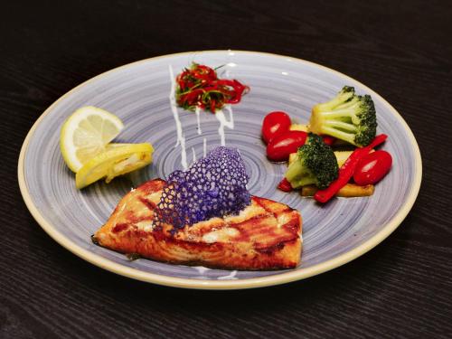 a plate of food with a piece of fish and vegetables at Mercure Iguazu Hotel Iru in Puerto Iguazú