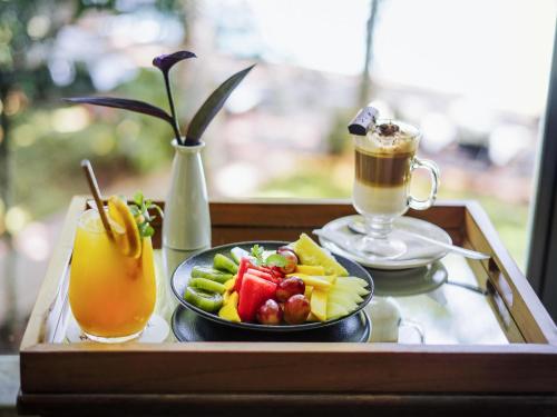 a tray with a plate of fruit and a drink at Mercure Iguazu Hotel Iru in Puerto Iguazú