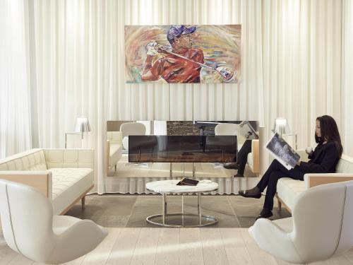a woman sitting in a living room with a piano at Mercure Hotel Golf Cap d'Agde in Cap d'Agde