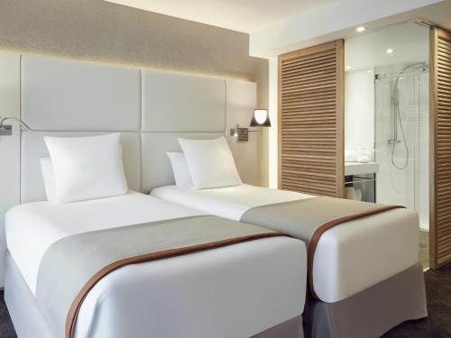 a bedroom with two beds and a shower at Mercure Hotel Golf Cap d'Agde in Cap d'Agde