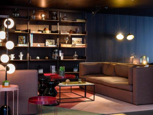 a living room with a couch and tables and shelves at Mercure Hotel Wiesbaden City in Wiesbaden