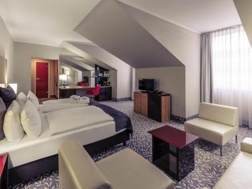 a hotel room with a bed and a chair at Mercure Hotel Wiesbaden City in Wiesbaden