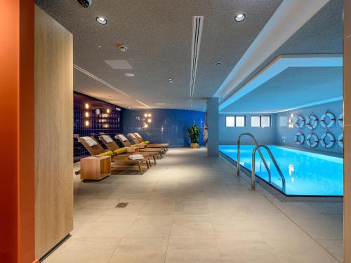 a room with a swimming pool and chairs in it at Mercure Hotel Wiesbaden City in Wiesbaden