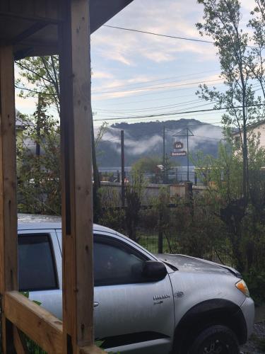 a car parked outside a house with a view of a mountain at Ecohpirén in Hornopiren