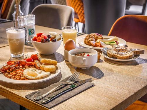 アムステルダムにあるメルキュール アムステルダム スローテルデイク ステーションの木製テーブル(朝食用の食品、ドリンク付)