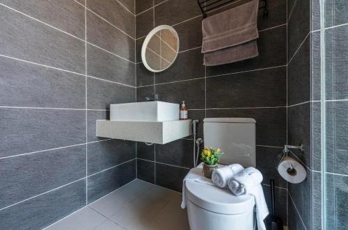a bathroom with a toilet with a sink and a mirror at Cozy Mayfair Homestay in Puchong