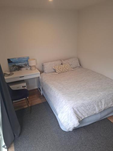 a small bedroom with a bed and a desk at TuiHideaway cozy studio sleepout in Mount Maunganui
