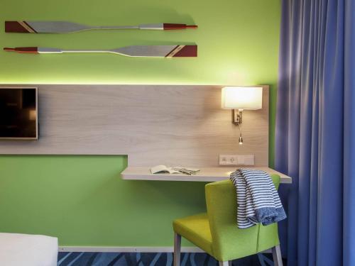 a room with a desk and a green wall at Ibis Styles Konstanz in Konstanz