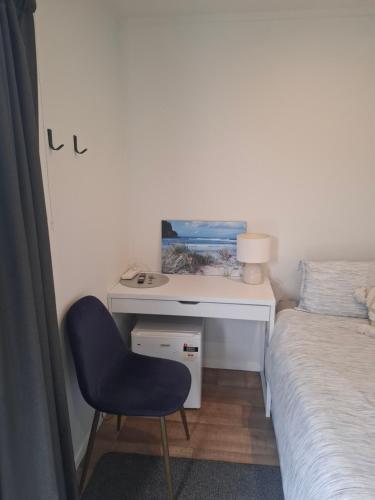 a bedroom with a desk with a bed and a chair at TuiHideaway cozy studio sleepout in Mount Maunganui