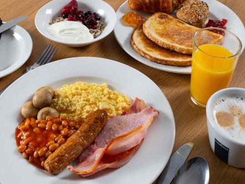 a table topped with plates of breakfast foods and orange juice at ibis Styles Crewe in Crewe