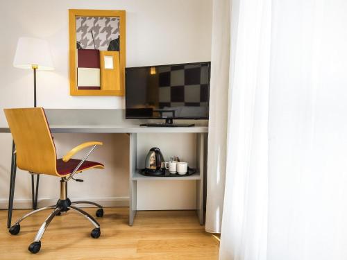 a room with a desk with a chair and a television at ibis Styles Haydock in Haydock