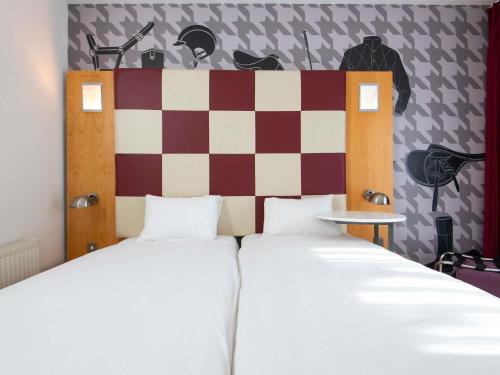 a bedroom with two beds and a checkered wall at ibis Styles Haydock in Haydock