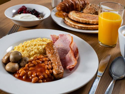two plates of breakfast food on a wooden table at ibis Styles Haydock in Haydock