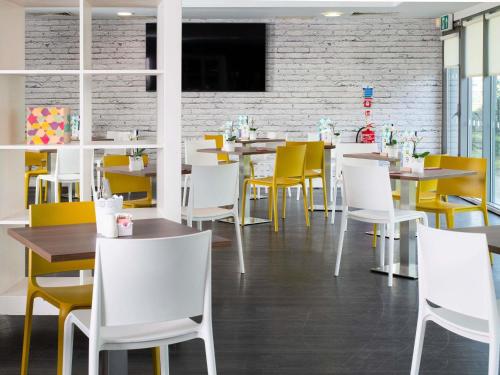 a dining room with tables and yellow chairs at ibis Styles Haydock in Haydock