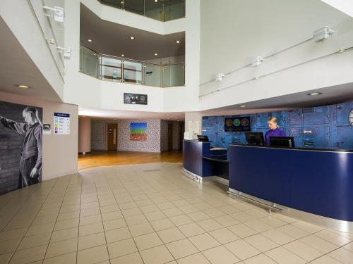 a woman sitting at a desk in a lobby at ibis Styles Barnsley in Barnsley