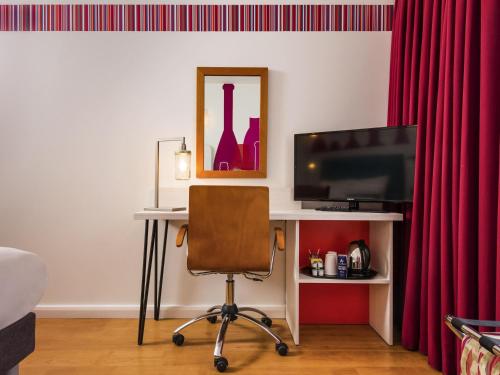 a desk with a television and a chair in a room at ibis Styles Barnsley in Barnsley