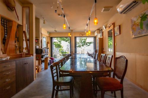 a dining room with a large wooden table and chairs at 民宿かまだ MinshukuKamada in Hatsukaichi