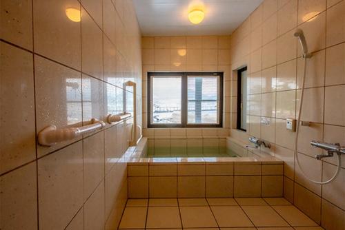 a large bathroom with a tub and a window at 民宿かまだ MinshukuKamada in Hatsukaichi