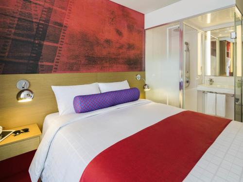 a bedroom with a red and white bed and a bathroom at ibis Styles Ambassador Seoul Myeong-dong in Seoul