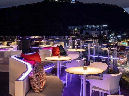 a row of tables and chairs on a balcony at night at ibis Styles Ambassador Seoul Myeong-dong in Seoul