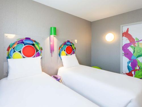 a bedroom with two beds and a colorful ball on the wall at ibis Styles Vierzon in Vierzon