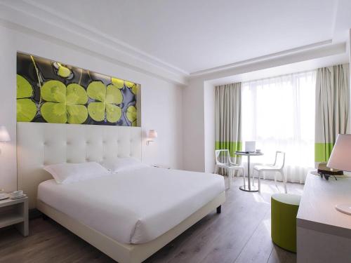a white bedroom with a large white bed and a table at ibis Styles Milano Est Settala in Settala
