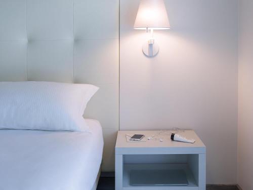 a bed with a side table with a lamp on it at ibis Styles Milano Est Settala in Settala