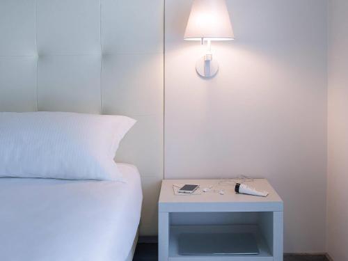 a bed and a table with a lamp on it at ibis Styles Milano Est Settala in Settala