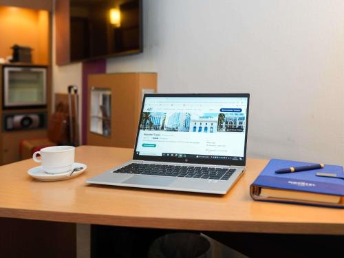 a laptop computer sitting on a desk with a cup of coffee at Novotel Tunis in Tunis