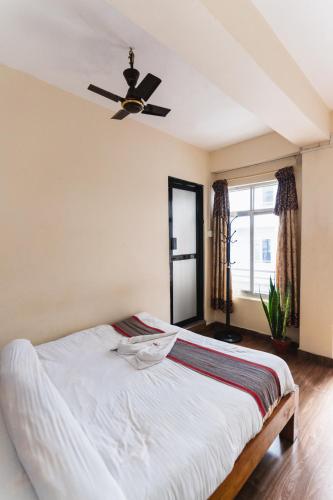 a bedroom with a bed with a ceiling fan at Santoshi Guest House and Yoga Center in Pokhara