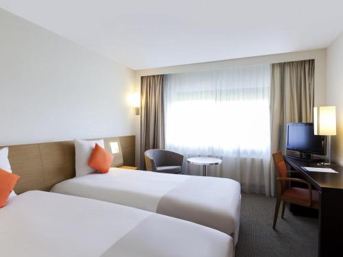 a hotel room with two beds and a television at Novotel Constantine in Constantine