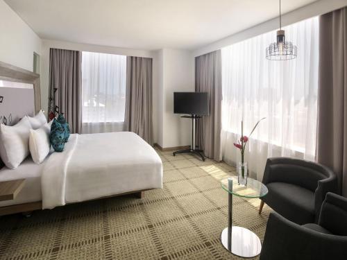 a hotel room with a large bed and a chair at Novotel Makassar Grand Shayla in Makassar