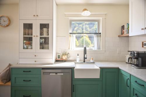 eine Küche mit grünen Schränken und einem Waschbecken in der Unterkunft Prairie Cottage, a Fresh Farmhouse in Snohomish