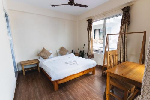 a bedroom with a bed and a desk and a window at Santoshi Guest House and Yoga Center in Pokhara