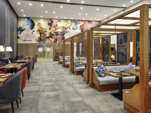 a restaurant with tables and chairs and a mural at Novotel Bali Ngurah Rai Airport in Kuta