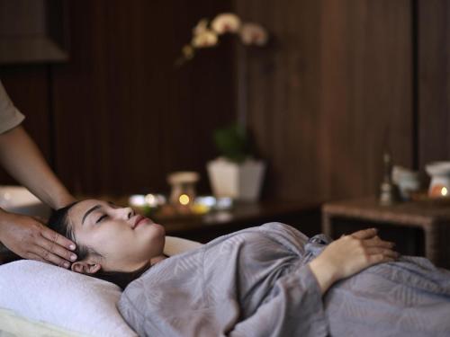 a woman laying in bed getting a massage at Novotel Bali Ngurah Rai Airport in Kuta