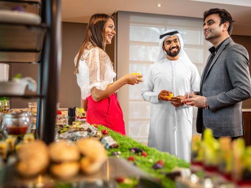 a man and a woman standing in front of a buffet at Pullman Dubai Jumeirah Lakes Towers in Dubai