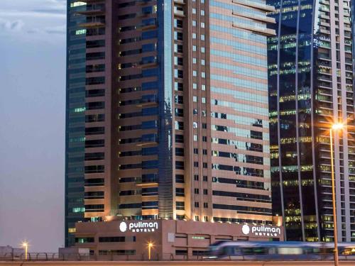 a large building with lights in front of it at Pullman Dubai Jumeirah Lakes Towers in Dubai