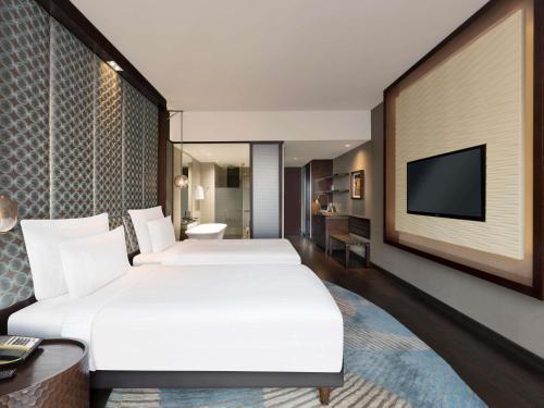 a hotel room with two beds and a flat screen tv at Pullman New Delhi Aerocity in New Delhi