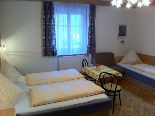 a room with two beds and a table and a couch at Hotel Tautermann in Innsbruck