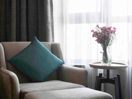 a living room with a chair and a vase of flowers at Pullman Taiyuan in Taiyuan
