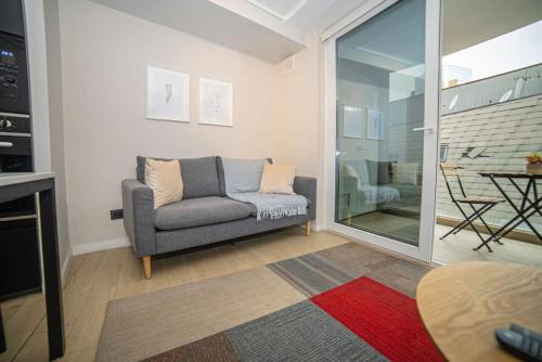 een woonkamer met een bank en een glazen schuifdeur bij Luxury Stay in a Prime 1BR in Santiago