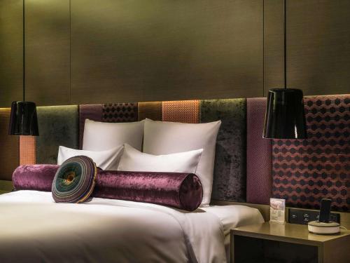 a bedroom with a bed with purple pillows at Pullman Nanjing Lukou Airport in Nanjing